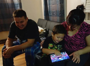 Jayden, using an iPad with his family