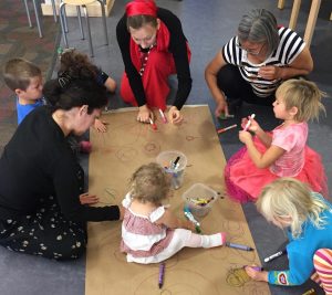 Children and caregivers participate in a collaborative art piece during storytime. Photo: Homer Public Library