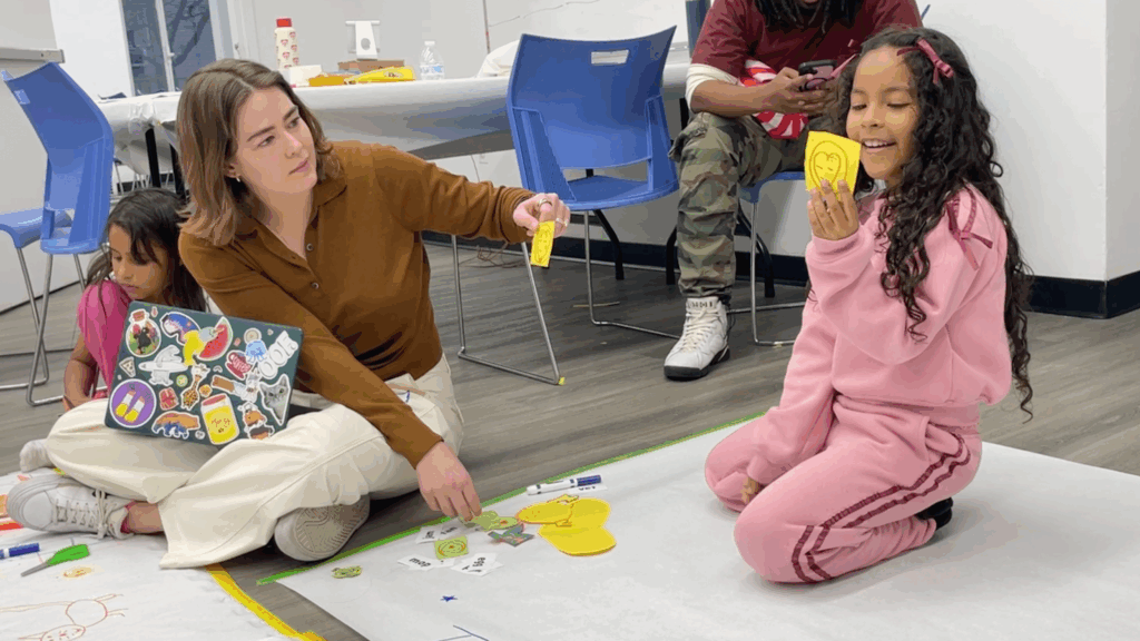 A girl holds a paper drawing during a co-design session with the Superfonik team.